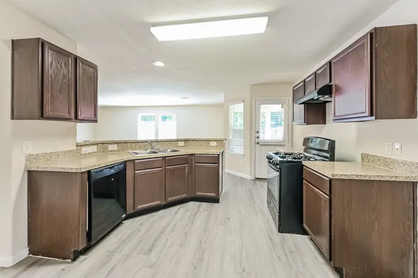 a kitchen with stainless steel appliances granite countertop a stove top oven a sink dishwasher and a microwave oven with cabinets