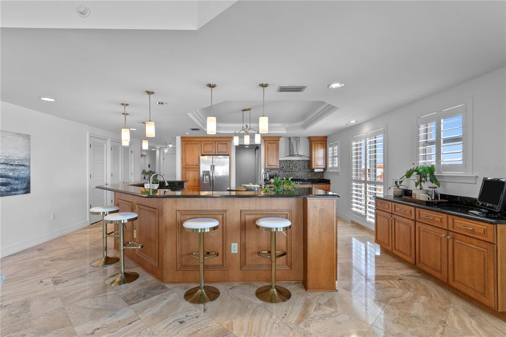19730 Gulf Boulevard, Unit 400 Indian Rocks Beach, FL 33785 - Photo 29 of 90 a kitchen with stainless steel appliances granite countertop a refrigerator a stove a sink a dining table and chairs with wooden floor