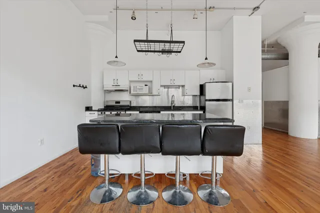 a kitchen with stainless steel appliances kitchen island granite countertop a table chairs and a wooden floor