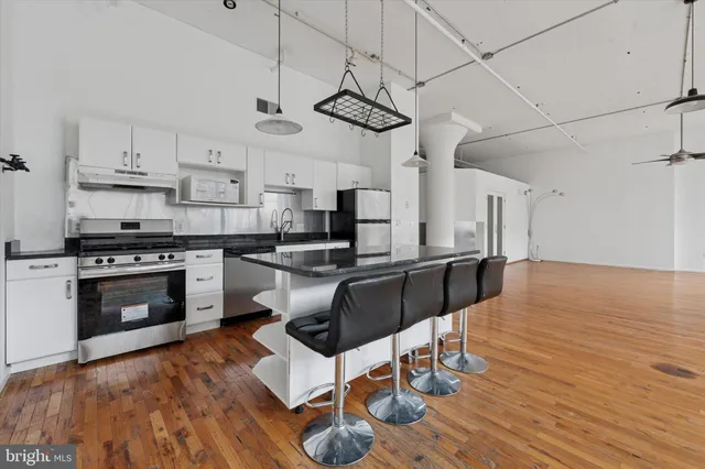 a kitchen with stainless steel appliances a stove a sink dishwasher a refrigerator white cabinets and wooden floor