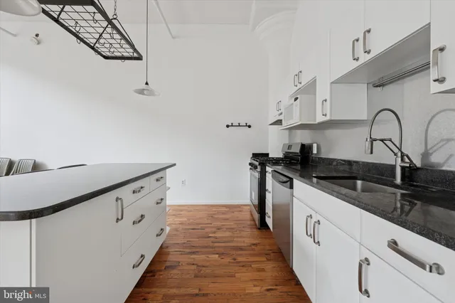 a kitchen with granite countertop white cabinets and black appliances