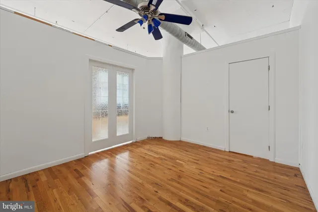 a view of empty room with wooden floor and fan