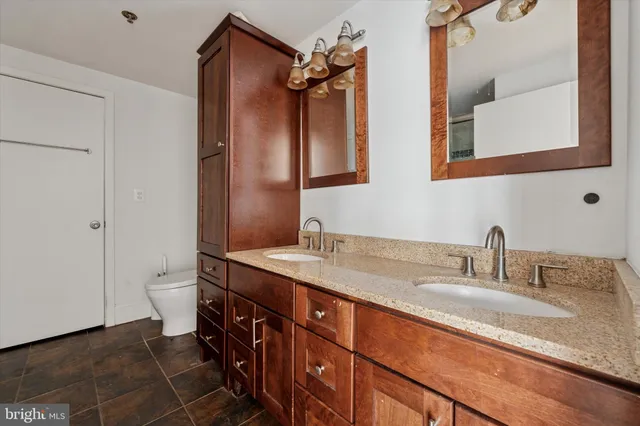 a bathroom with a granite countertop sink a toilet and a mirror