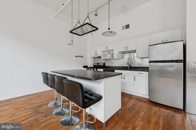 a kitchen with stainless steel appliances granite countertop a sink a stove a refrigerator and island with wooden floor