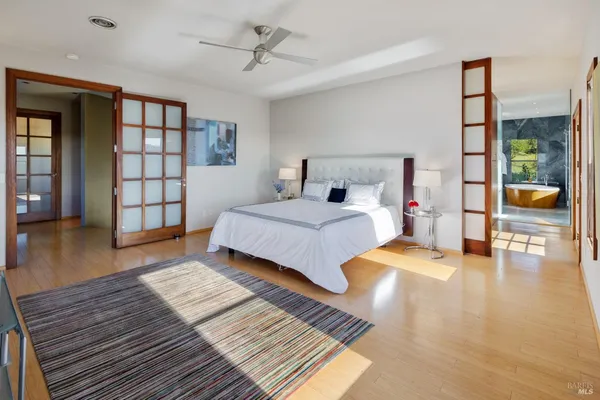 a bedroom with a large bed a chandelier and windows