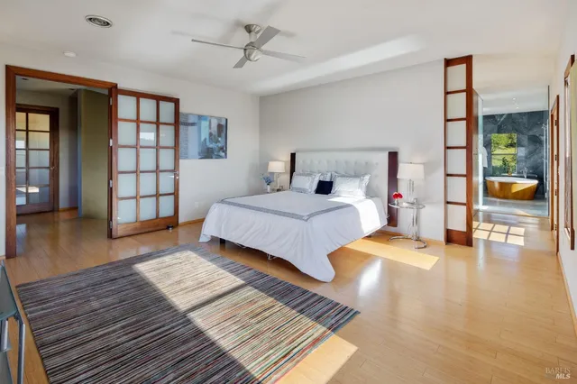 a bedroom with a large bed a chandelier and windows