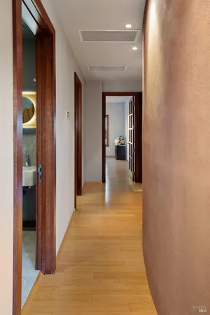 a view of a hallway with wooden floor and living room