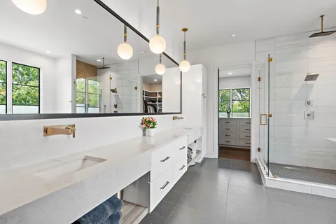 a bathroom with a double vanity sink and mirror with bathtub