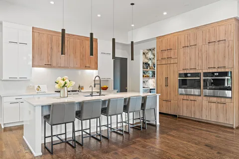 a kitchen with stainless steel appliances granite countertop a stove top oven a refrigerator a sink and white cabinets with wooden floor