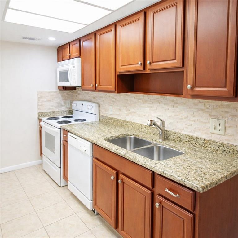 5273 Vineland Road, Unit 103 Orlando, FL 32811 - Photo 4 of 8 a kitchen with stainless steel appliances granite countertop a sink stove and cabinets