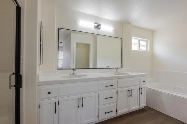 a bathroom with double vanity two mirror and a bathtub