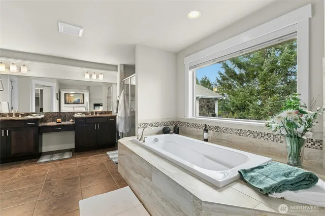 a spacious bathroom with a tub a double vanity sink and mirror