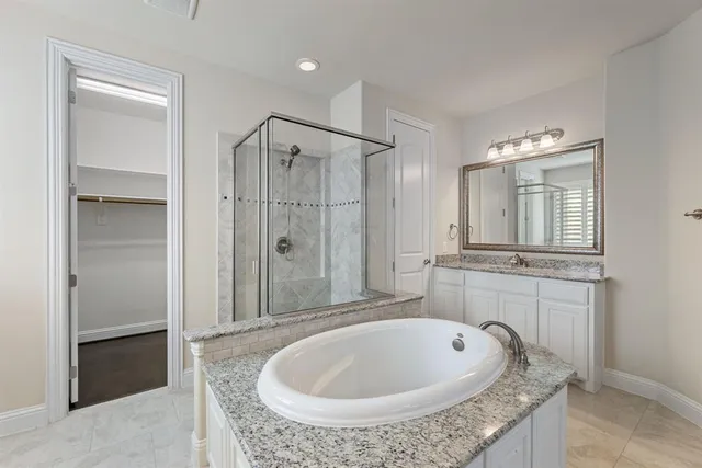 a bathroom with a granite countertop sink a mirror and a bathtub