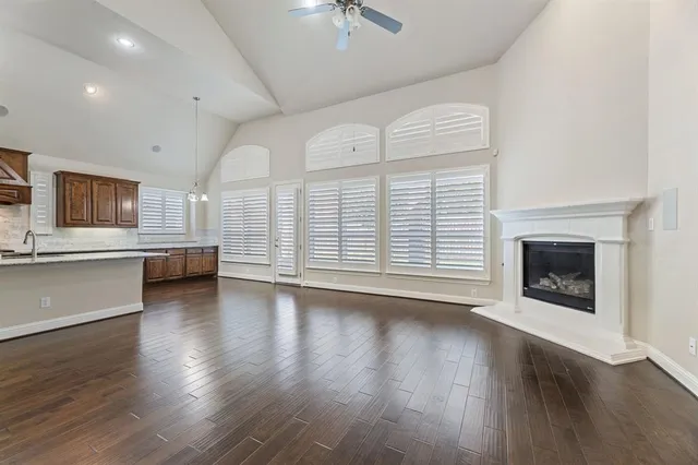 a view of a kitchen and an empty room with wooden floor and a fireplace