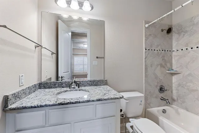 a bathroom with a granite countertop sink a mirror and a bathtub