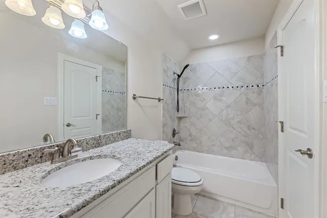 a bathroom with a granite countertop sink a toilet and bathtub