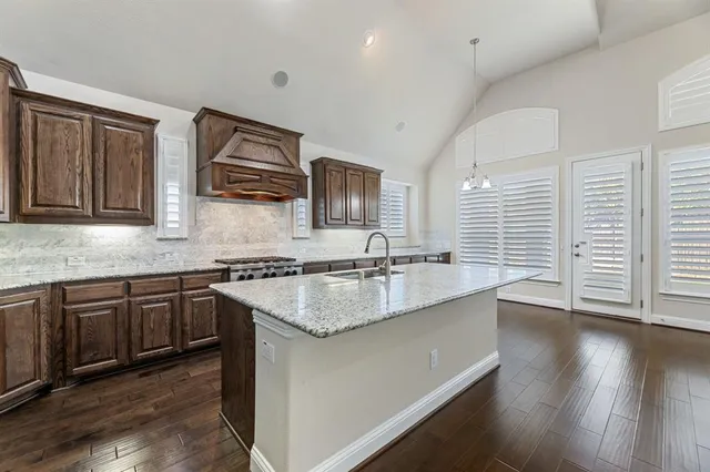 a kitchen with stainless steel appliances granite countertop a sink stove and wooden cabinets