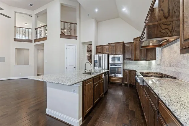 a kitchen with stainless steel appliances granite countertop a stove a sink and a refrigerator