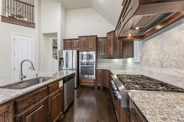 a kitchen with stainless steel appliances granite countertop a stove a sink and a refrigerator