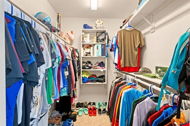 a view of walk in closet with clothes and shoes