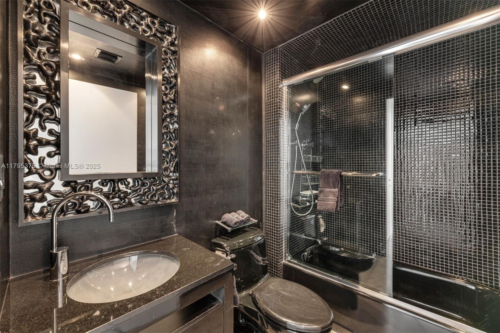 450 Alton Road, Unit 2303 Miami Beach, FL 33139 - Photo 21 of 51 a bathroom with a sink a toilet a mirror and shower