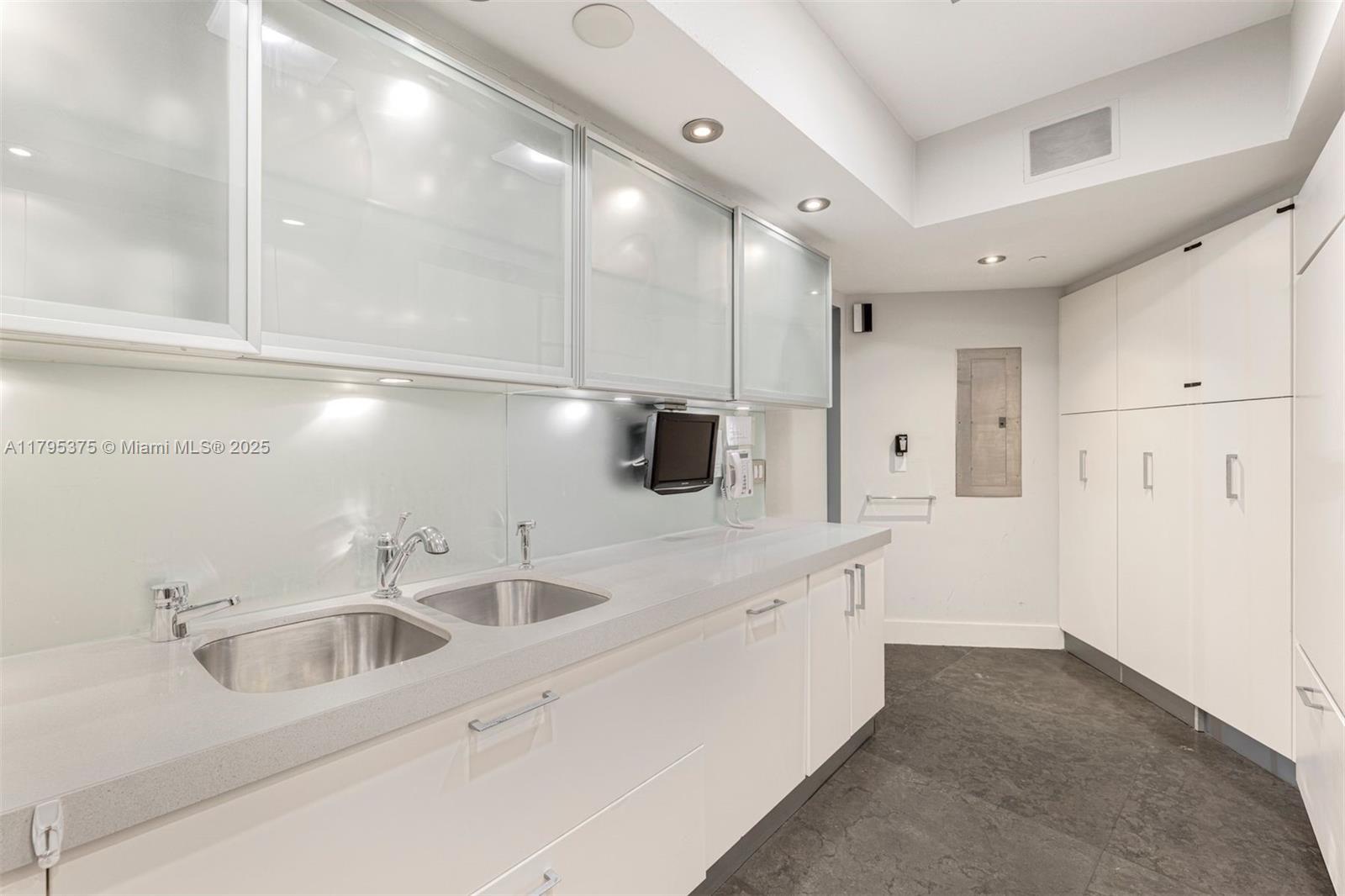 450 Alton Road, Unit 2303 Miami Beach, FL 33139 - Photo 24 of 51 a kitchen with stainless steel appliances a sink a refrigerator and a cabinets