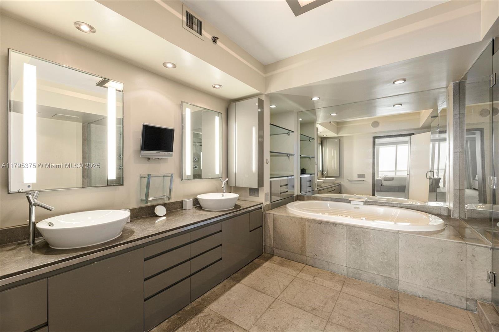 450 Alton Road, Unit 2303 Miami Beach, FL 33139 - Photo 10 of 51 a bathroom with a double vanity sink a mirror and a bathtub