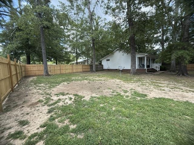 395 Austin Street Savannah, TN 38372 - Photo 23 of 32 Spacious rear yard featuring a newly installed privacy fence, mature trees, and a white-sided residence with a covered porch and white railing