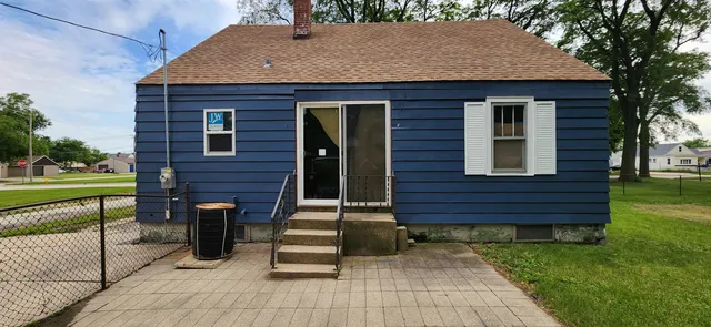 a brick house with a yard potted plants and a large tree
