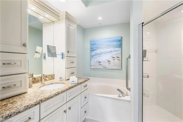 a bathroom with a granite countertop sink a mirror a bathtub and shower