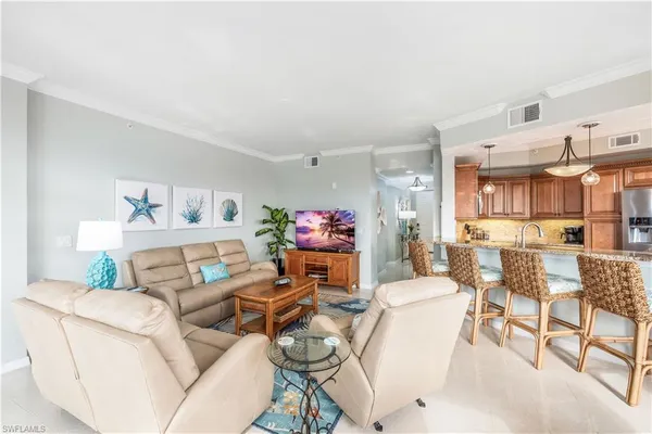a living room with furniture and a dining table with kitchen appliances