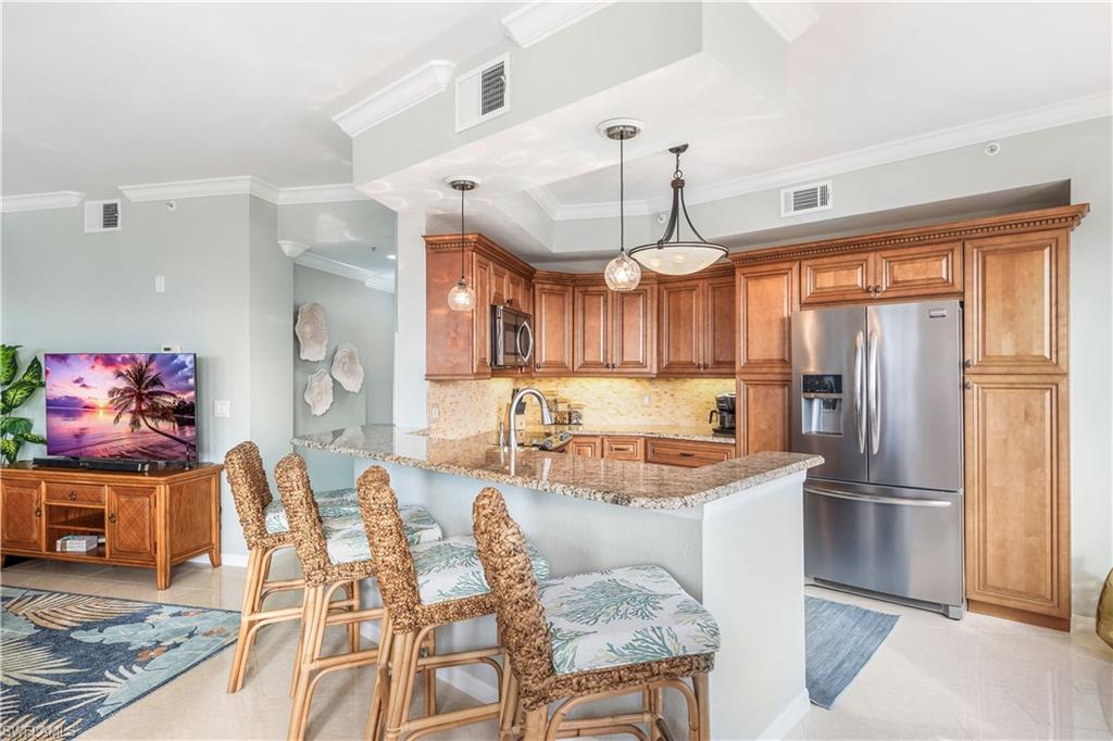170 Lenell Road, Unit 401 Fort Myers Beach, FL 33931 - Photo 6 of 24 a kitchen with stainless steel appliances granite countertop a refrigerator a sink dishwasher a dining table and chairs with wooden floor
