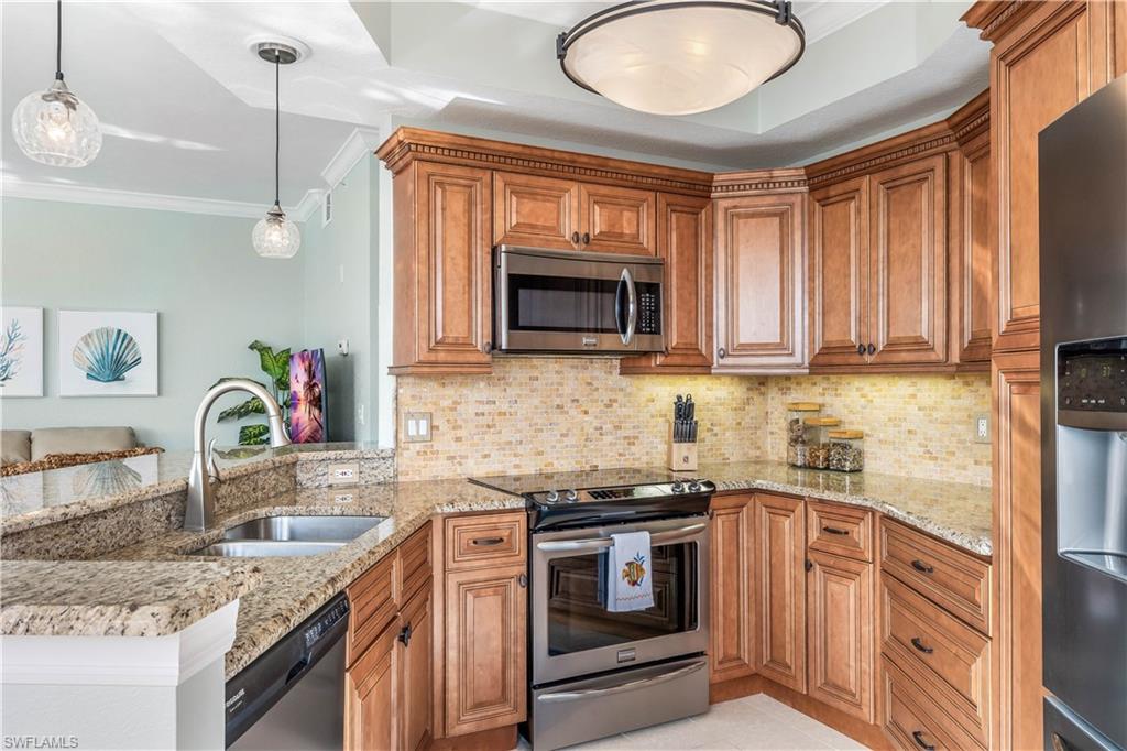 170 Lenell Road, Unit 401 Fort Myers Beach, FL 33931 - Photo 7 of 24 a kitchen with stainless steel appliances granite countertop a sink a stove a microwave a refrigerator and cabinets