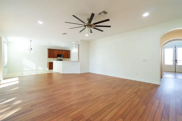 a view of empty room with wooden floor and ceiling fan