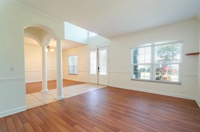 a view of an empty room with wooden floor and a window