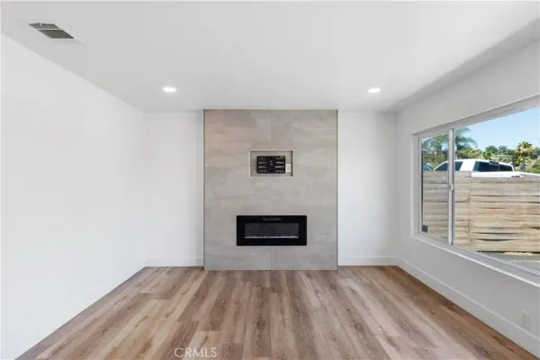 a view of an empty room with a fireplace and a window
