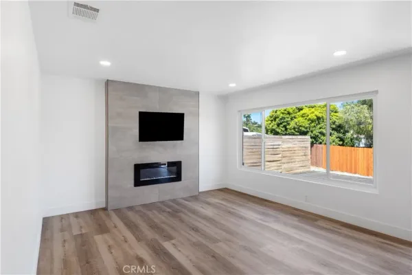 an empty room with windows fireplace and wooden floor