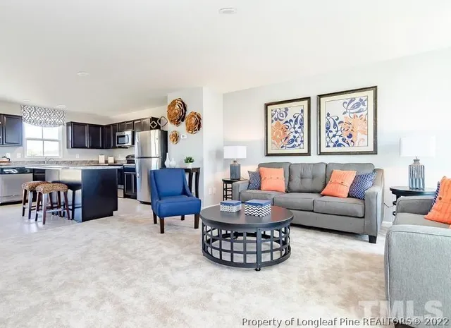 a living room with furniture a rug and kitchen view