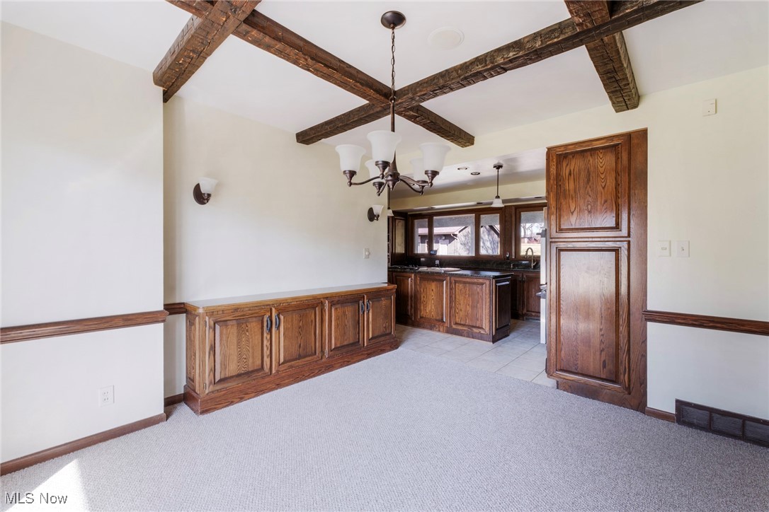7059 Stewart Sharon Road Hubbard, OH 44425 - Photo 25 of 49 Kitchen with baseboards, visible vents, light carpet, beamed ceiling, and a notable chandelier