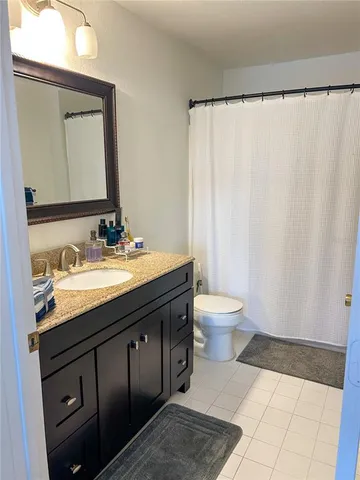 a bathroom with a granite countertop sink toilet and a mirror