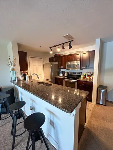 a kitchen with stainless steel appliances granite countertop a sink a stove and a refrigerator