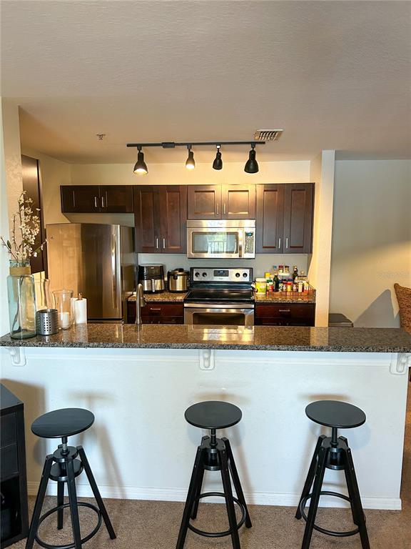 5447 Vineland Road, Unit 1209 Orlando, FL 32811 - Photo 7 of 27 a kitchen with stainless steel appliances kitchen island granite countertop a sink and a refrigerator