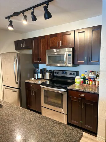 a kitchen with granite countertop stainless steel appliances a stove a refrigerator and cabinets