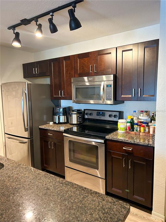 5447 Vineland Road, Unit 1209 Orlando, FL 32811 - Photo 8 of 27 a kitchen with granite countertop stainless steel appliances a stove a refrigerator and cabinets