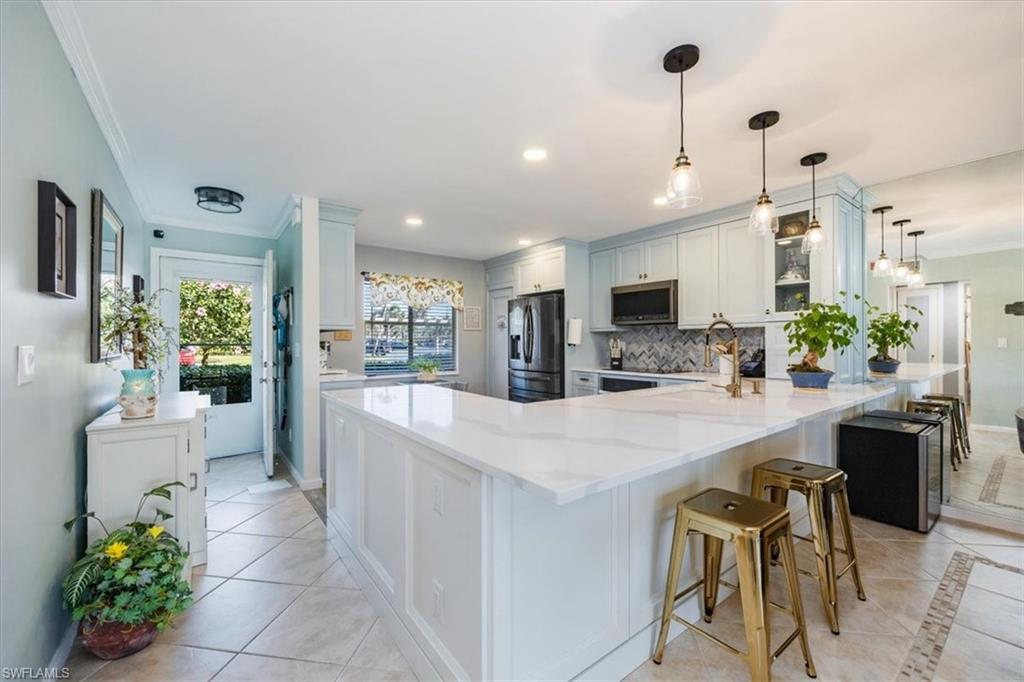 4572 Andover Way, Unit C102 Naples, FL 34112 - Photo 1 of 48 a kitchen with stainless steel appliances kitchen island granite countertop a refrigerator a stove a sink a dining table and chairs with wooden floor