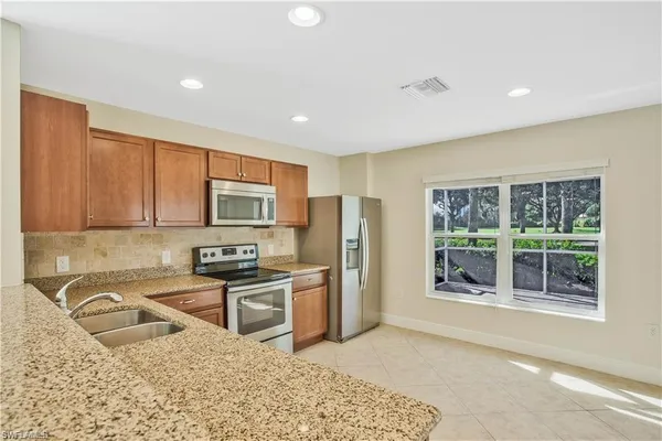 a kitchen with stainless steel appliances granite countertop a refrigerator stove top oven and sink