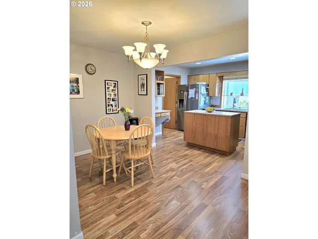 a dining room with wooden floor a chandelier a wooden table and chairs