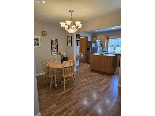 a dining room with wooden floor a chandelier a wooden table and chairs