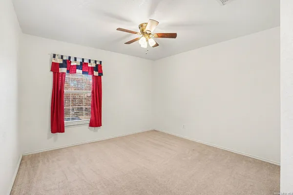 a view of an empty room with a chandelier fan and a window