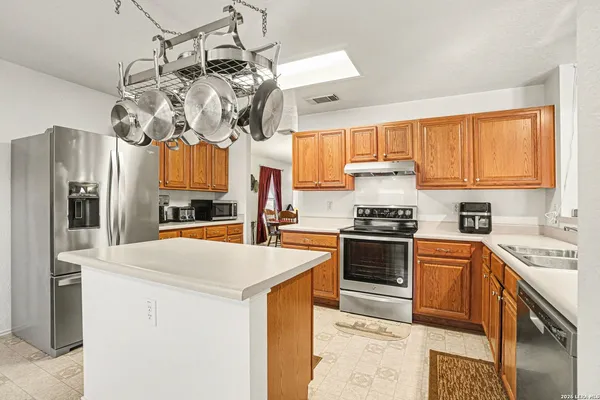 a kitchen with stainless steel appliances granite countertop a sink a stove a refrigerator cabinets and a window